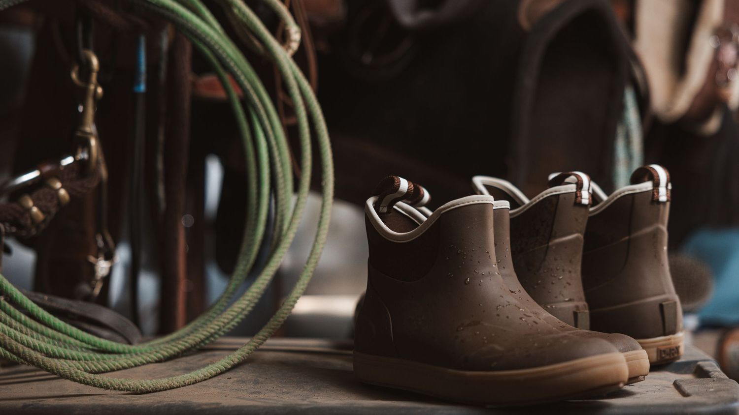 Detailed macro photography sequence showing brown leather boots and green laces being threaded through metal eyelets.