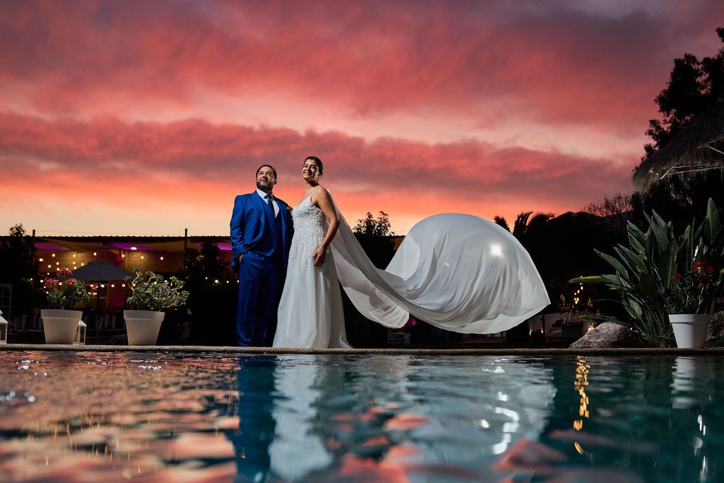 Intimate romantic wedding scene near window showing couple embracing in a rustic cabin setting.