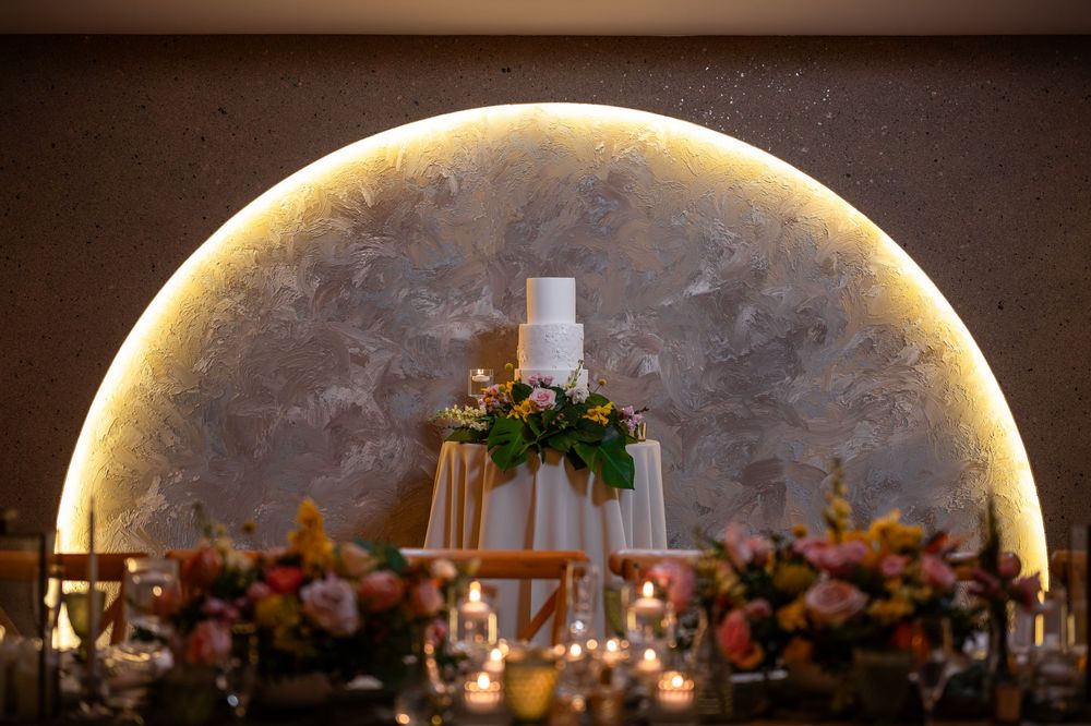 Illuminated wedding arch with floral arrangements and candles creating a romantic backdrop.