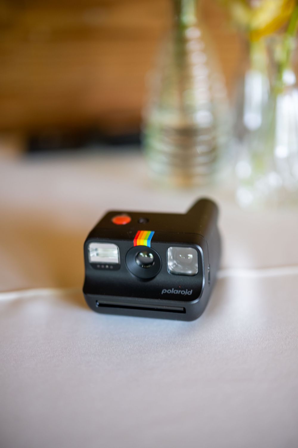 Black Polaroid instant camera placed on white tablecloth at wedding reception.