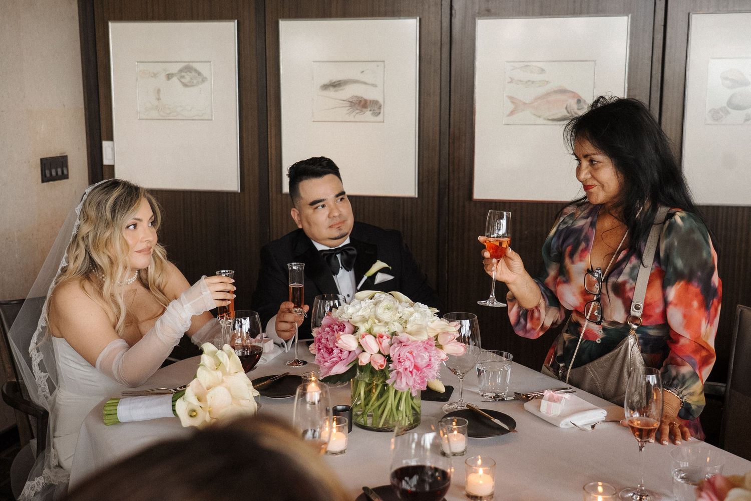 Party guests socializing and enjoying drinks and conversation around a dining table at a festive gathering.