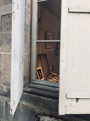 A sneak peek through a window into a room with canvas, brushes and artwork