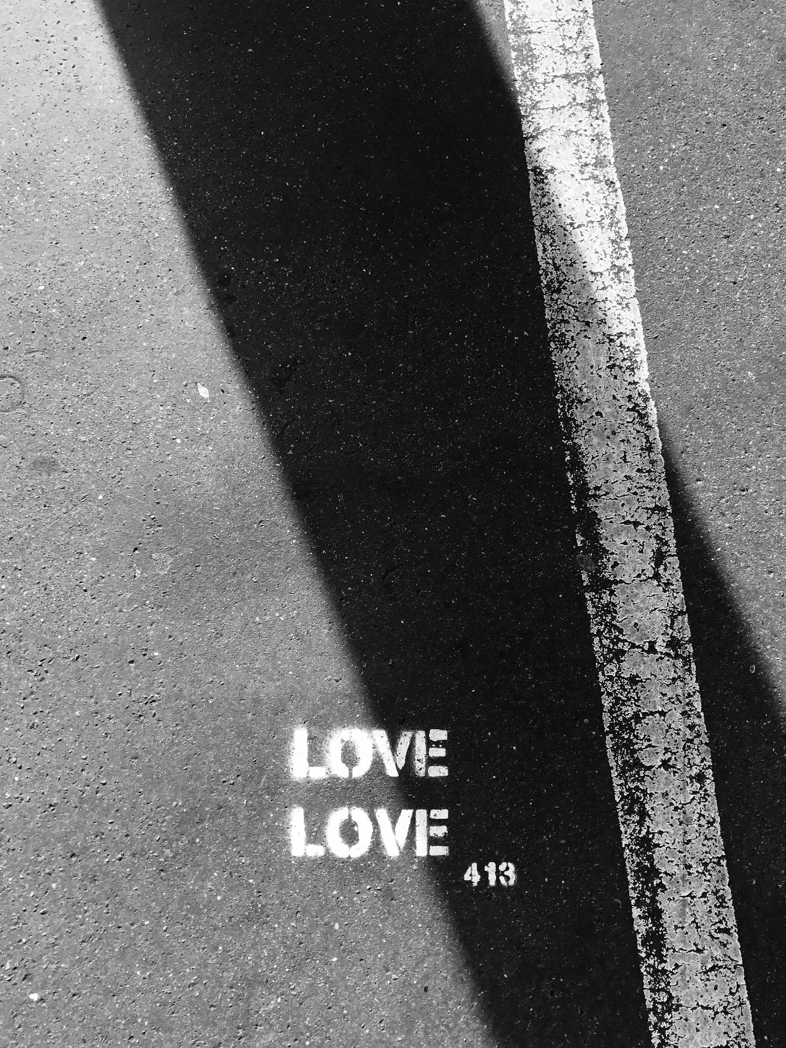 Black and white photo of the word "Love" painted on asphalt