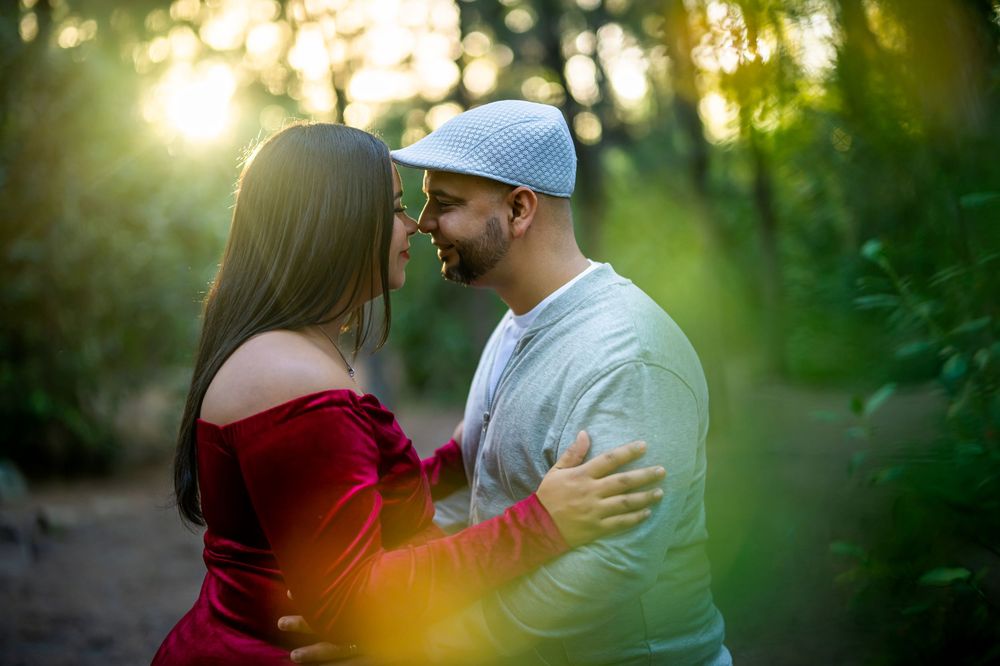 A couple in casual attire sharing romantic moments outdoors during golden hour in a natural setting.