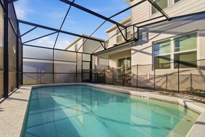 Covered swimming pool with clear blue water surrounded by glass panels and white structural beams.