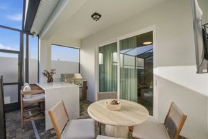 Modern apartment interior with white walls and wooden furniture features large windows and natural lighting throughout.
