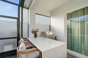 Modern balcony with white terrazzo table, wooden chairs, and frosted glass panels creating a sleek outdoor living space.
