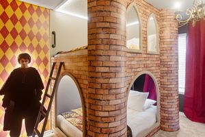 Rustic hotel room interior with exposed brick columns, diamond pattern wallpaper, and modern furnishings.
