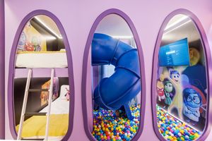 Colorful ball pit and play area visible through airplane-style windows in a children's entertainment facility.