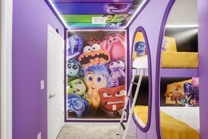 Interior view of a colorful themed room with animated character wall mural and purple archway design.