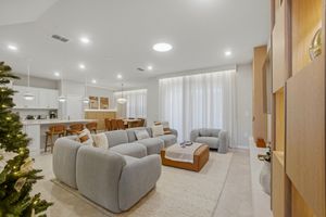 Modern white and beige open concept living room with recessed lighting and sleek sectional sofa.