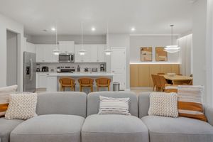 Modern living room features a grey sectional sofa with decorative pillows and open concept design leading to dining area.