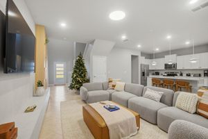 Modern basement renovation features white walls, recessed lighting, and a cozy living area with grey furniture and holiday decor.