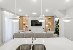 Modern white kitchen interior with pendant lights, wood accents, and sleek minimalist design features.