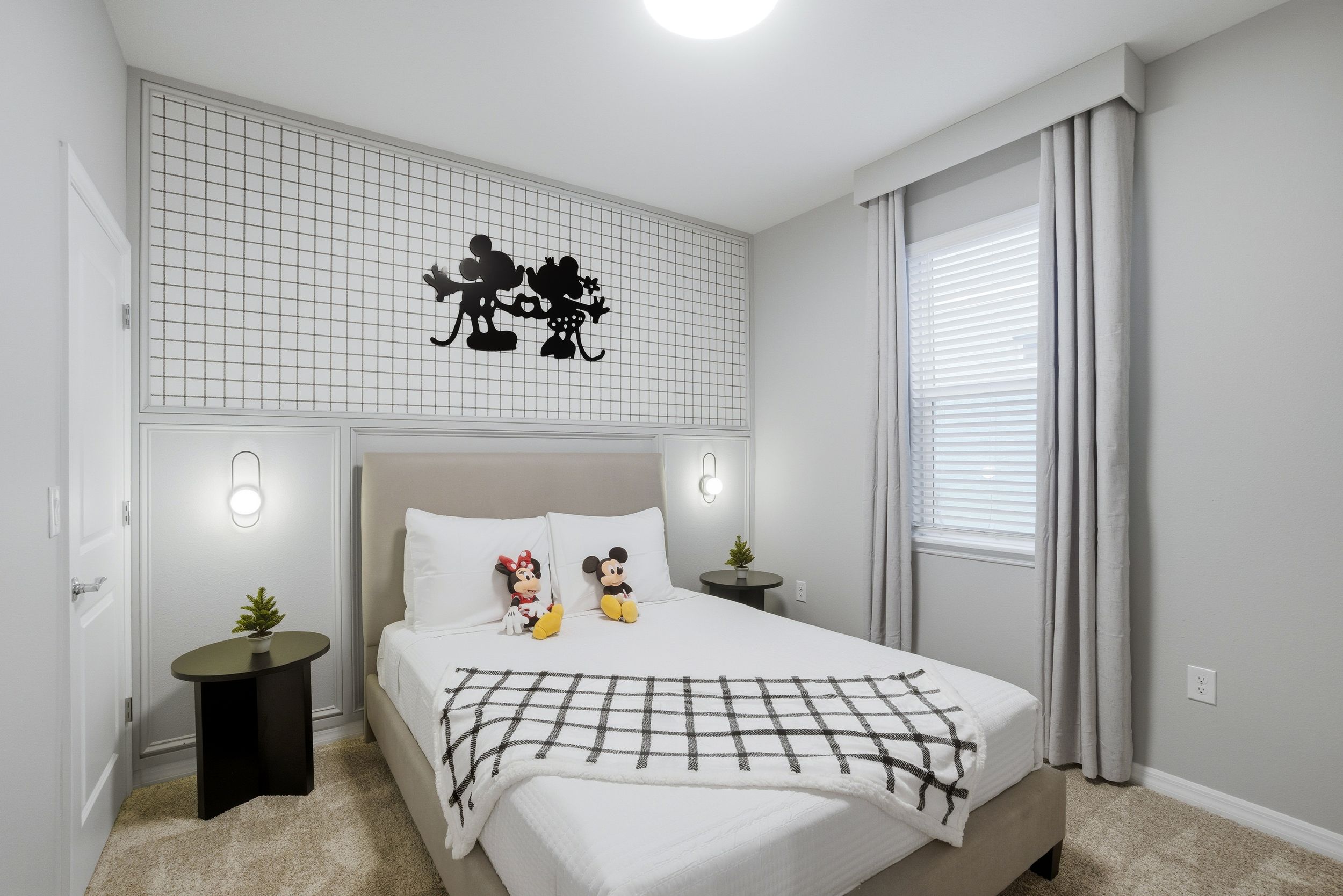 Modern bedroom interior with white walls, hardwood floors, and large windows letting in natural light.