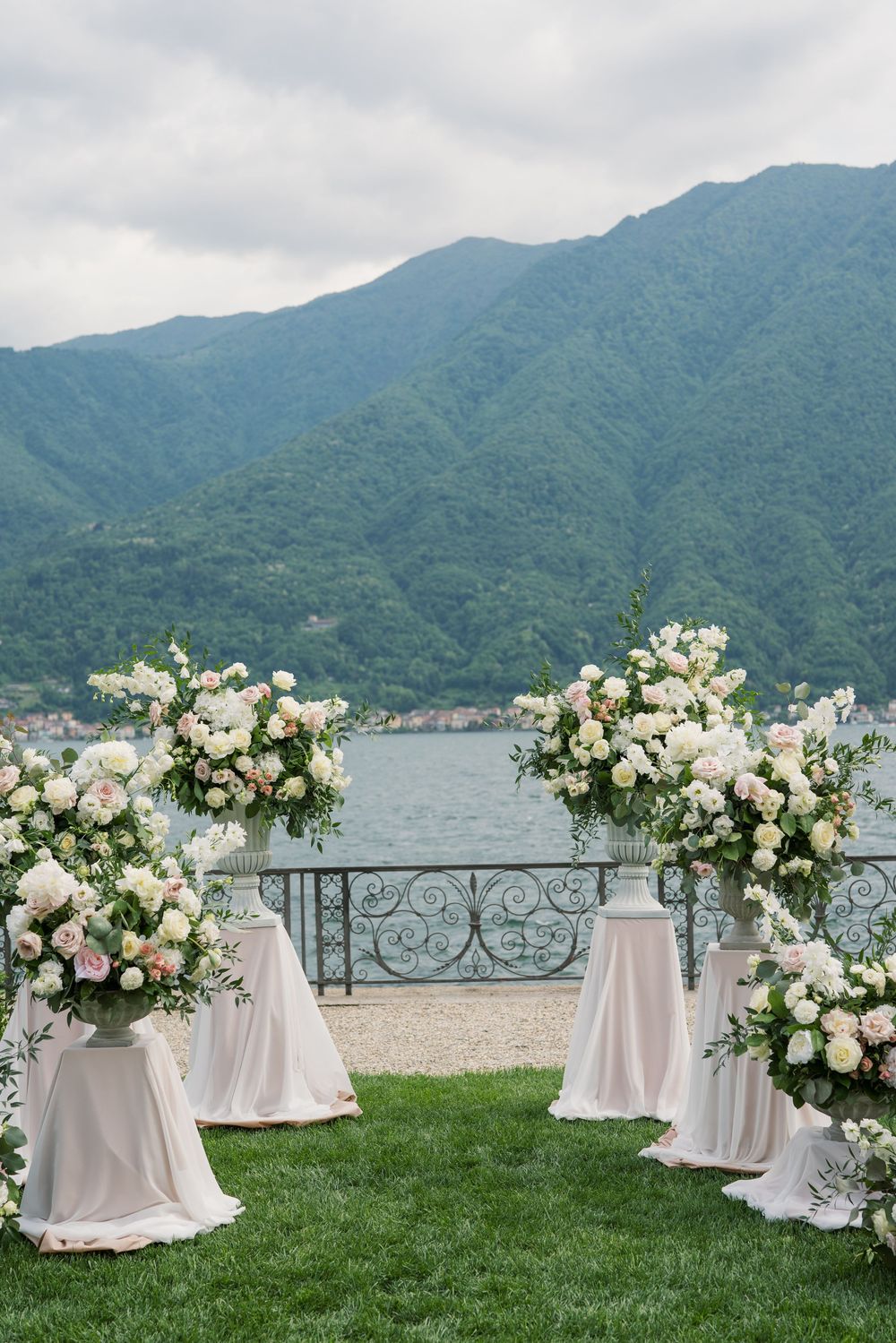 Outdoor wedding altar with white floral arrangements and mountain lake scenery.