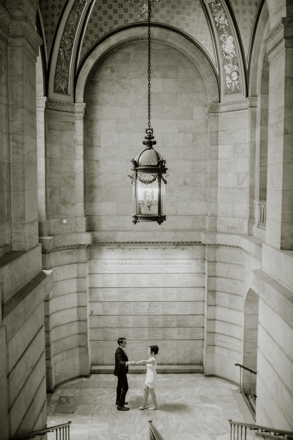 Black and white photo of elegant stone stairwell with hanging vintage lantern.