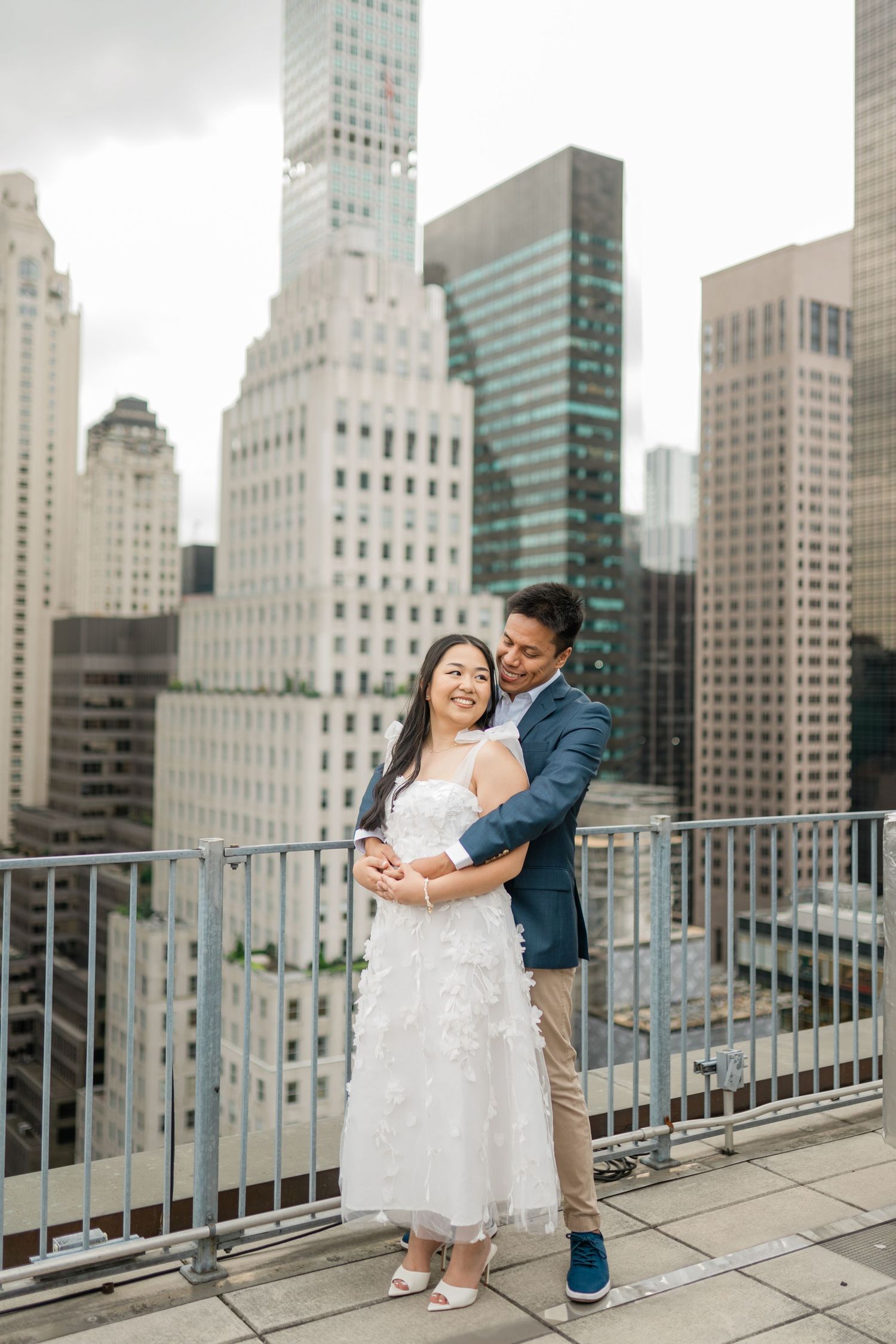 Couple sharing a tender moment on a rooftop with Manhattan skyline in background.