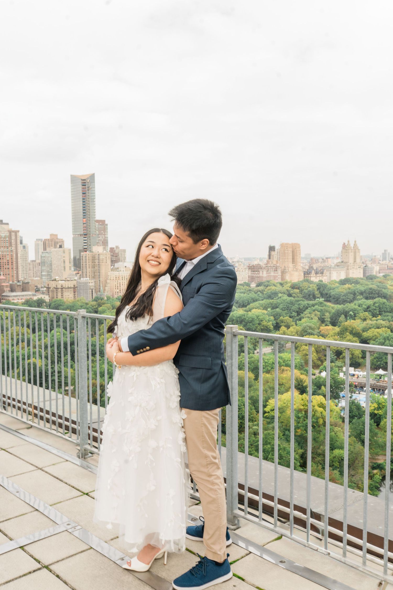 Dancing together on a terrace with panoramic views of Central Park and city buildings.