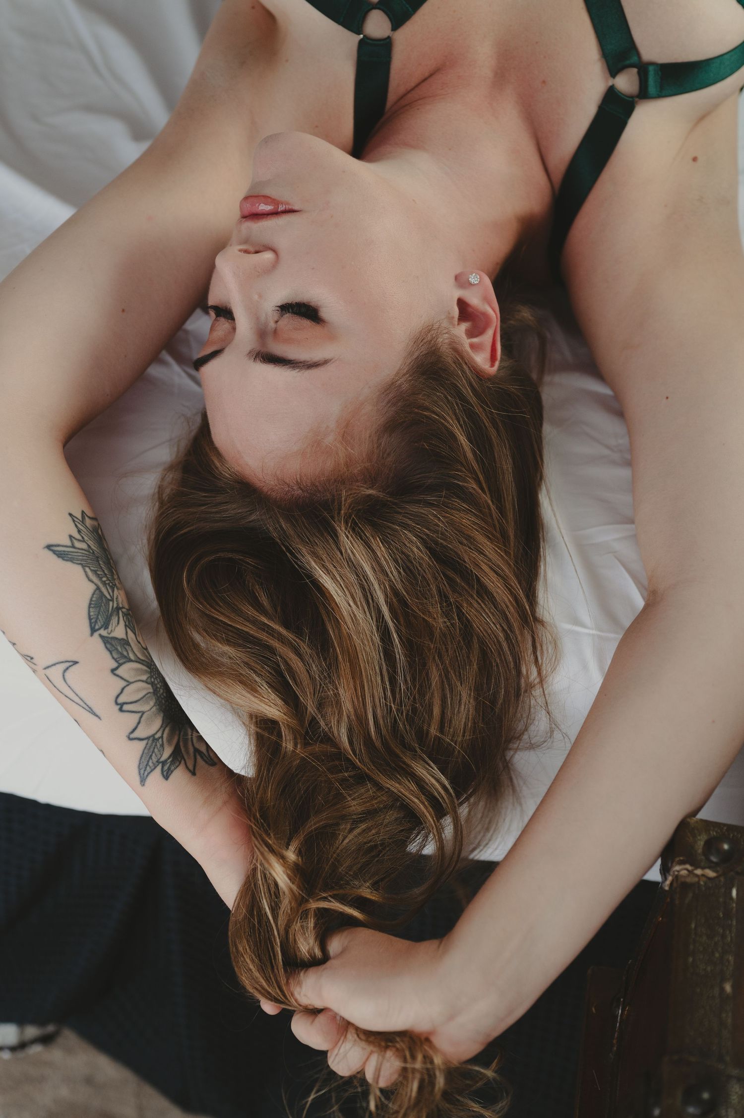 Artistic boudoir photography series showing intimate poses on white bedding with visible floral tattoo artwork.