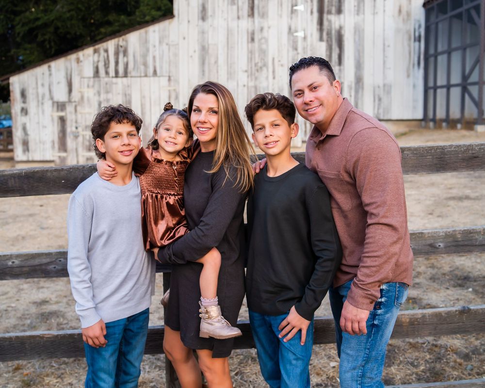 A smiling group poses together outdoors against a concrete wall background for a casual portrait.