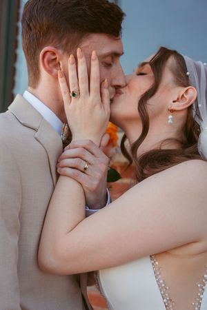 Wedding couple shares an intimate kiss against a soft blurred background.