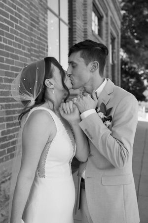Intimate black and white portrait of newlyweds sharing tender moment in formal attire.