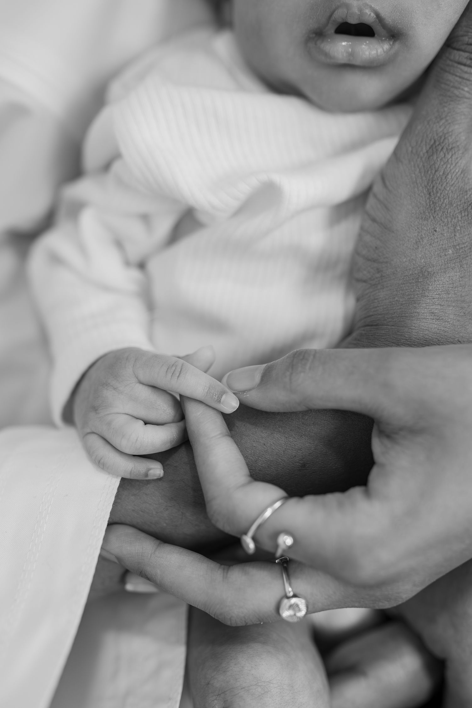 Mustavalkoinen lähikuva äidin ja vauvan käsistä. Vauvakuvaus, lapsikuvaus, baby photography.