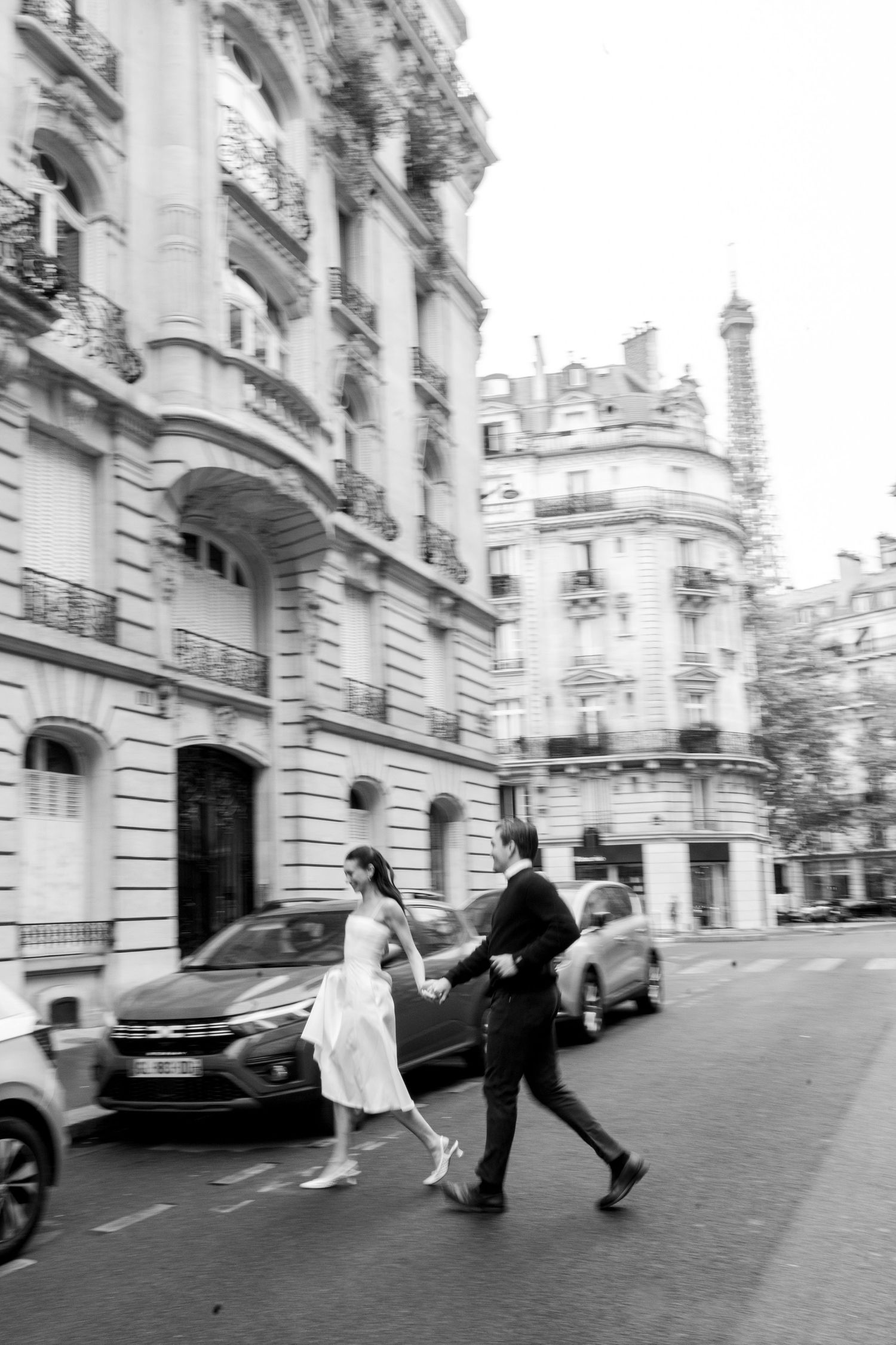 A person in a flowy white dress spins gracefully in front of an elegant beige stone building with large wooden doors.
