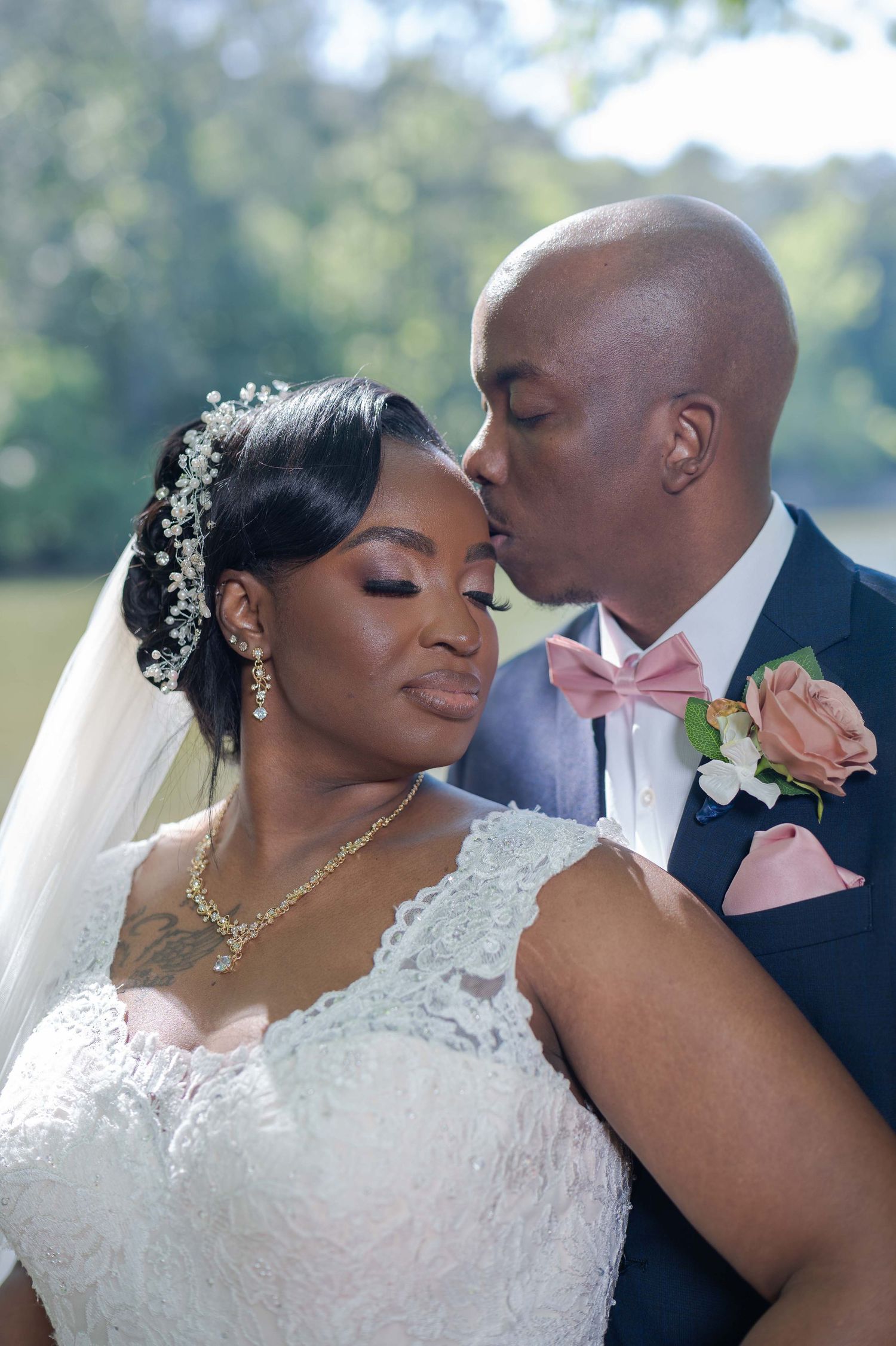 A tender moment between newlyweds in formal wedding attire with delicate floral accessories and jewelry.