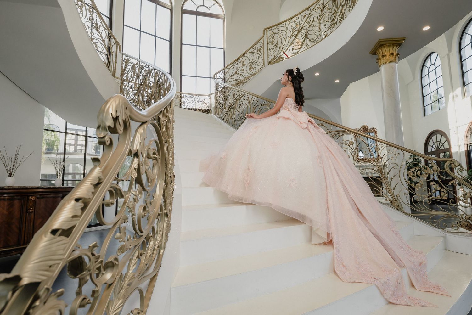 Sweeping portrait shots of a princess ballgown against ornate gold railings in a luxury venue.