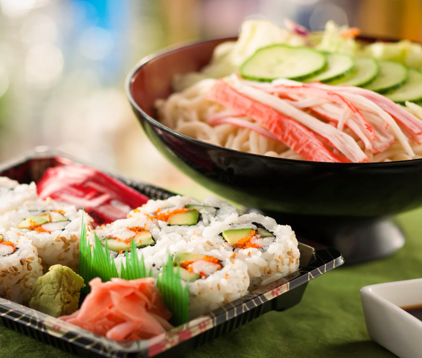 Fresh sushi rolls and sashimi served with garnishes in black bowls.