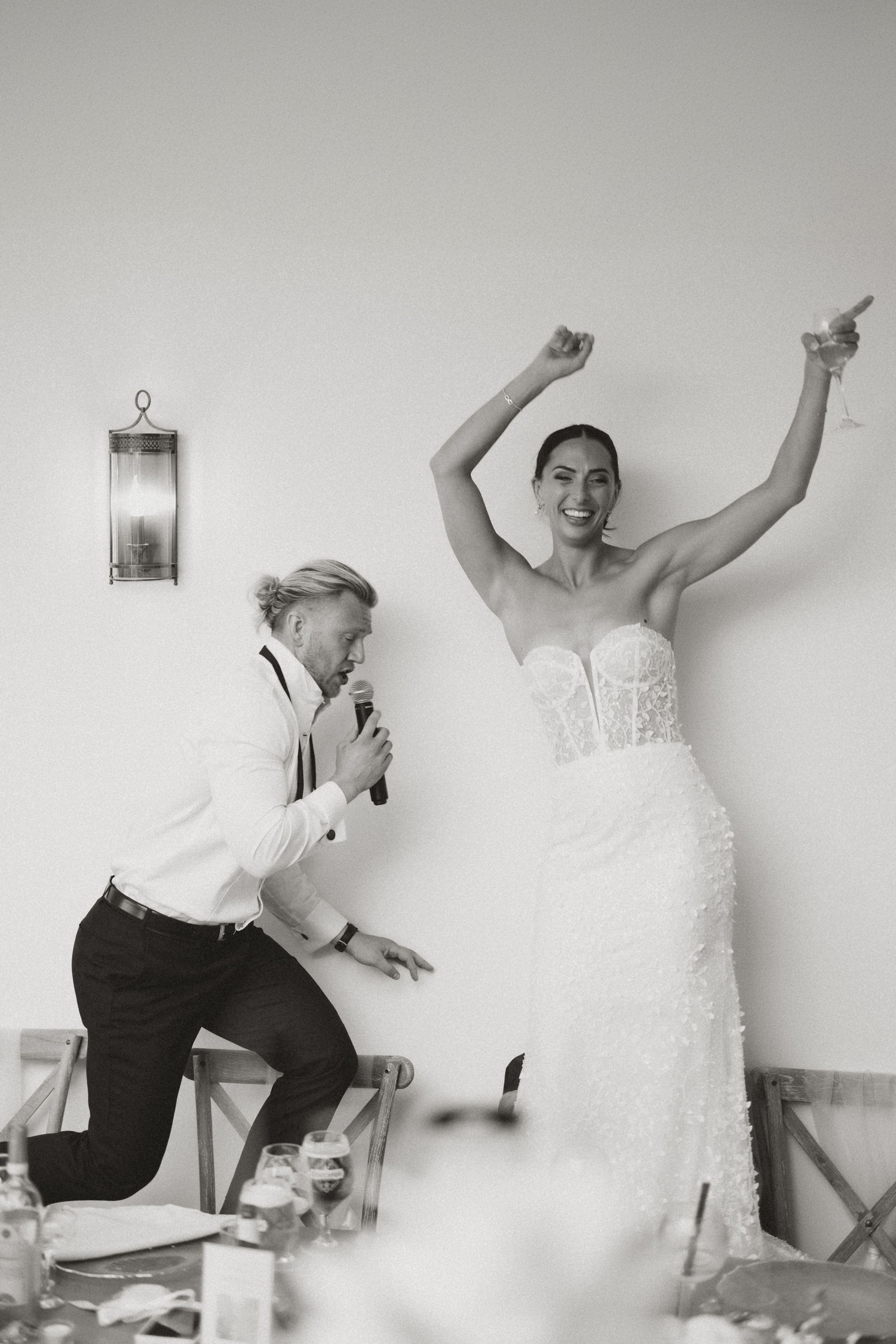 A celebratory moment at a wedding reception with two people dancing energetically in formal attire.