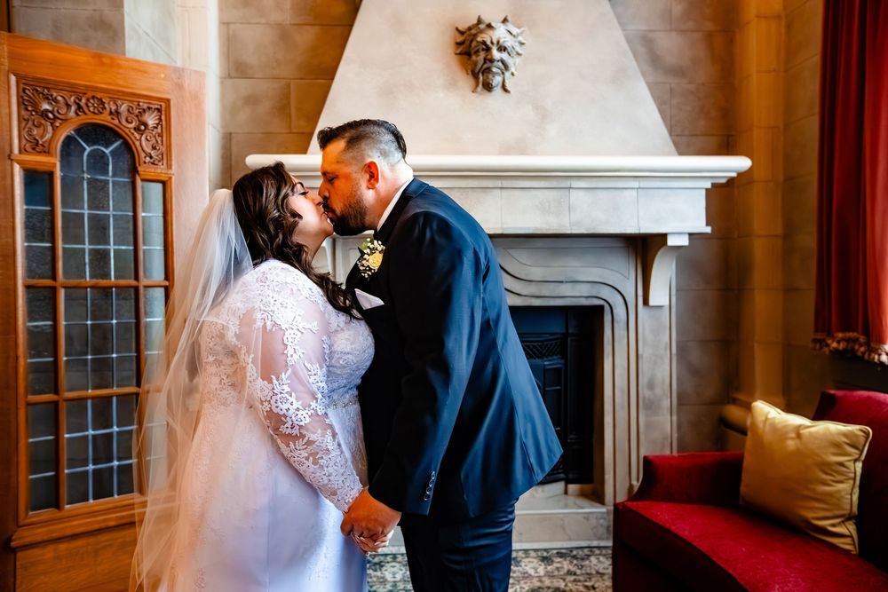 A couple shares an intimate moment during their wedding in an elegant room with ornate decor and wood paneling.