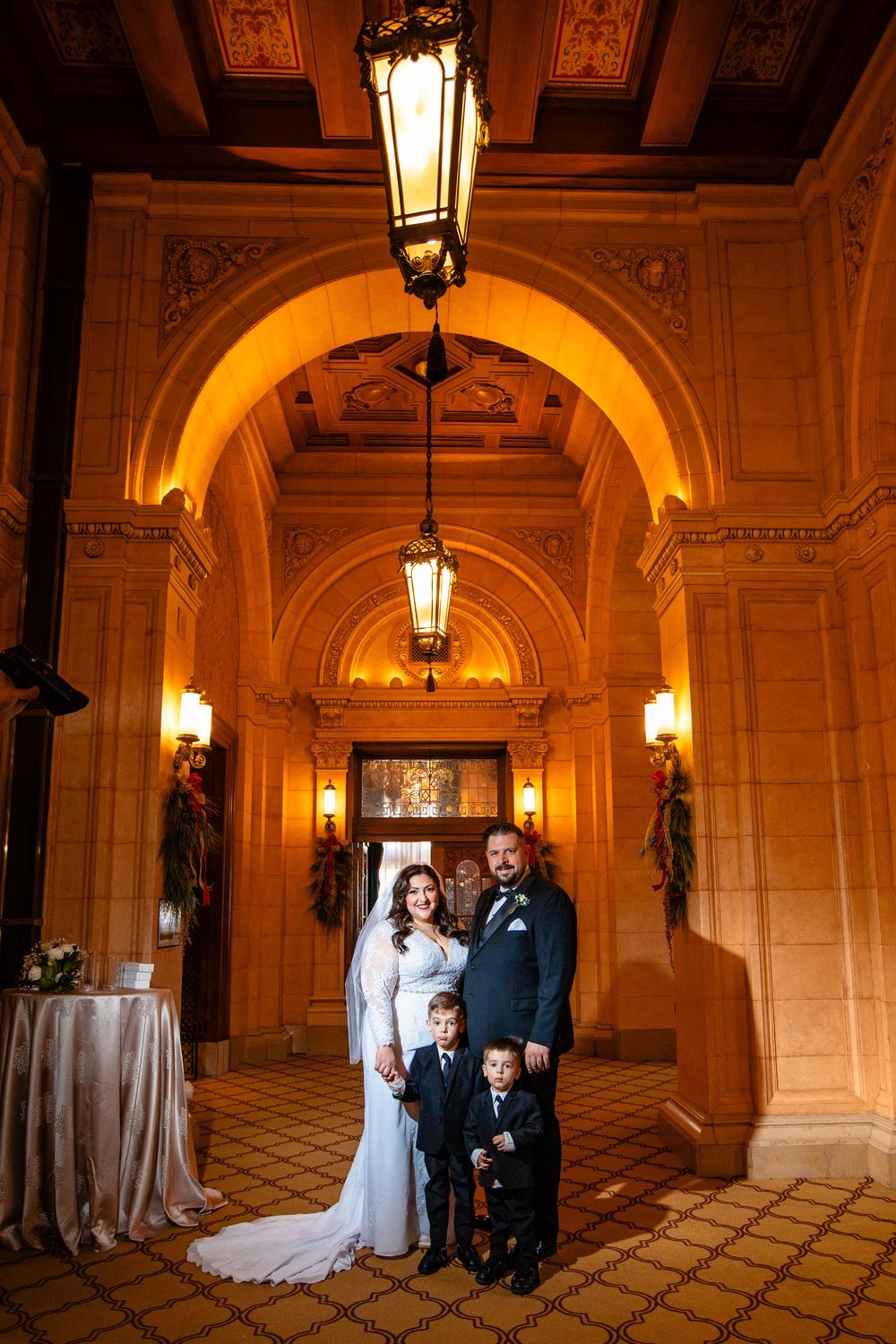 Elegant wedding portraits taken in an ornate hallway with arched ceilings and warm lighting.