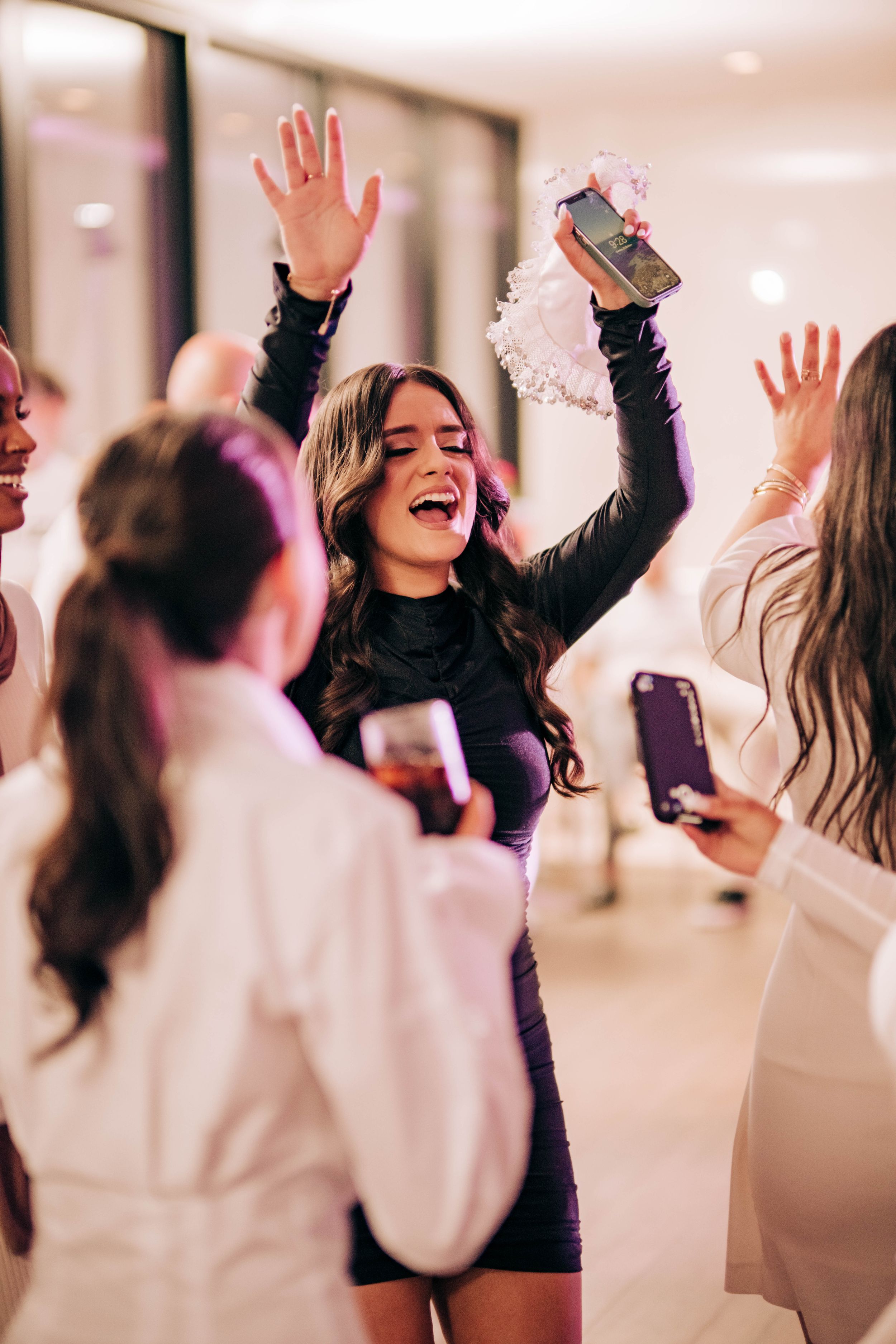 A group of people raise their hands together in celebration at an indoor event.
