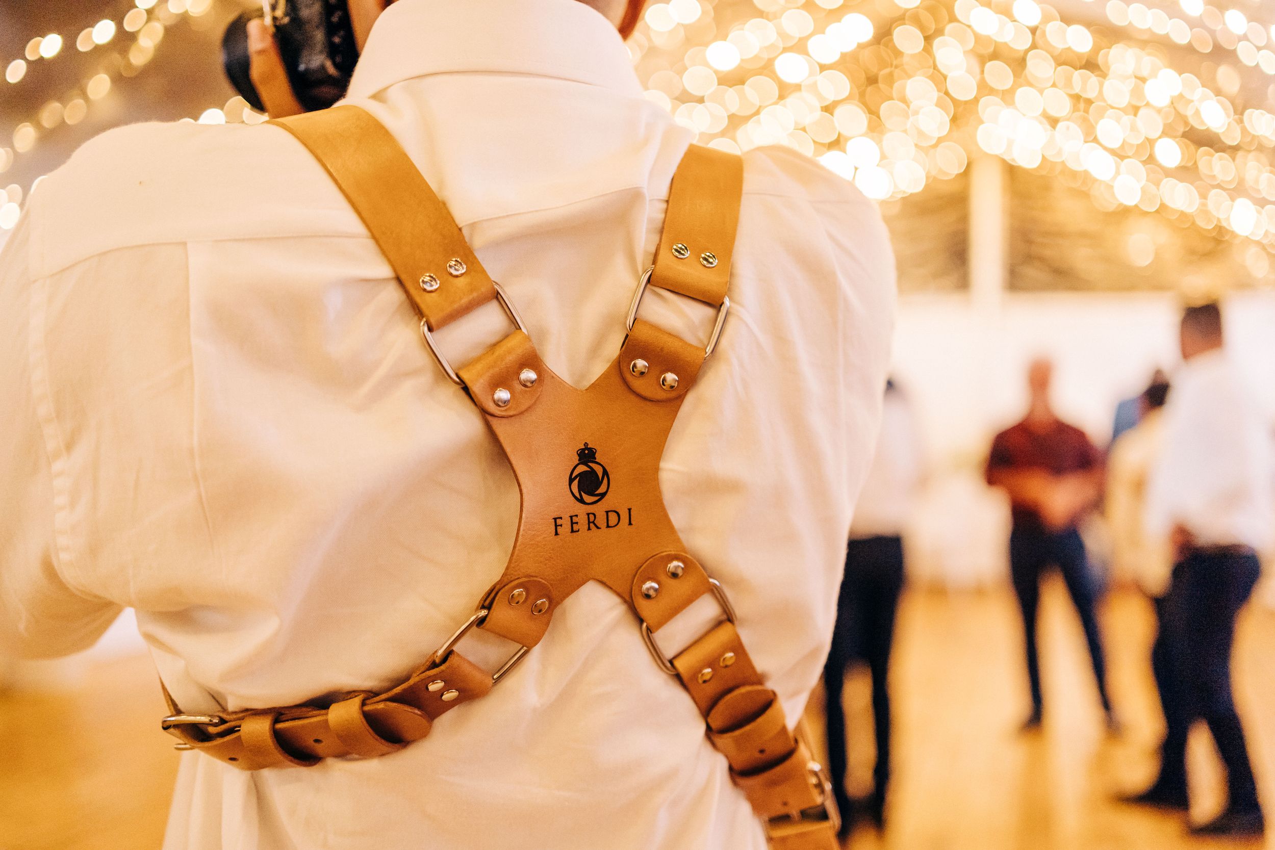 A pair of leather harness shoes sits on a hardwood floor, lit with warm, ambient lighting against a blurred background.