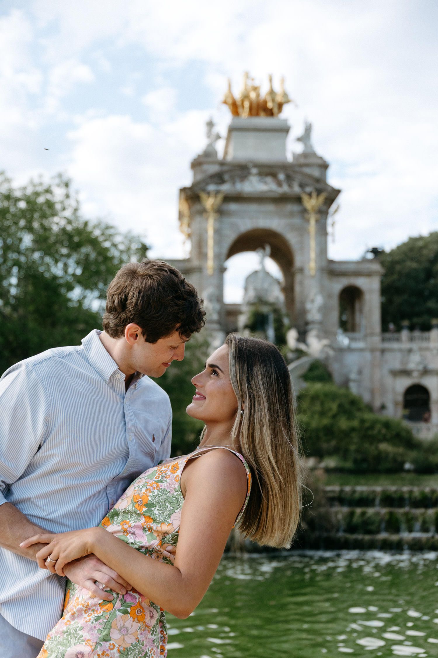 Couple shares tender moments by ornate architectural fountain in a romantic setting.
