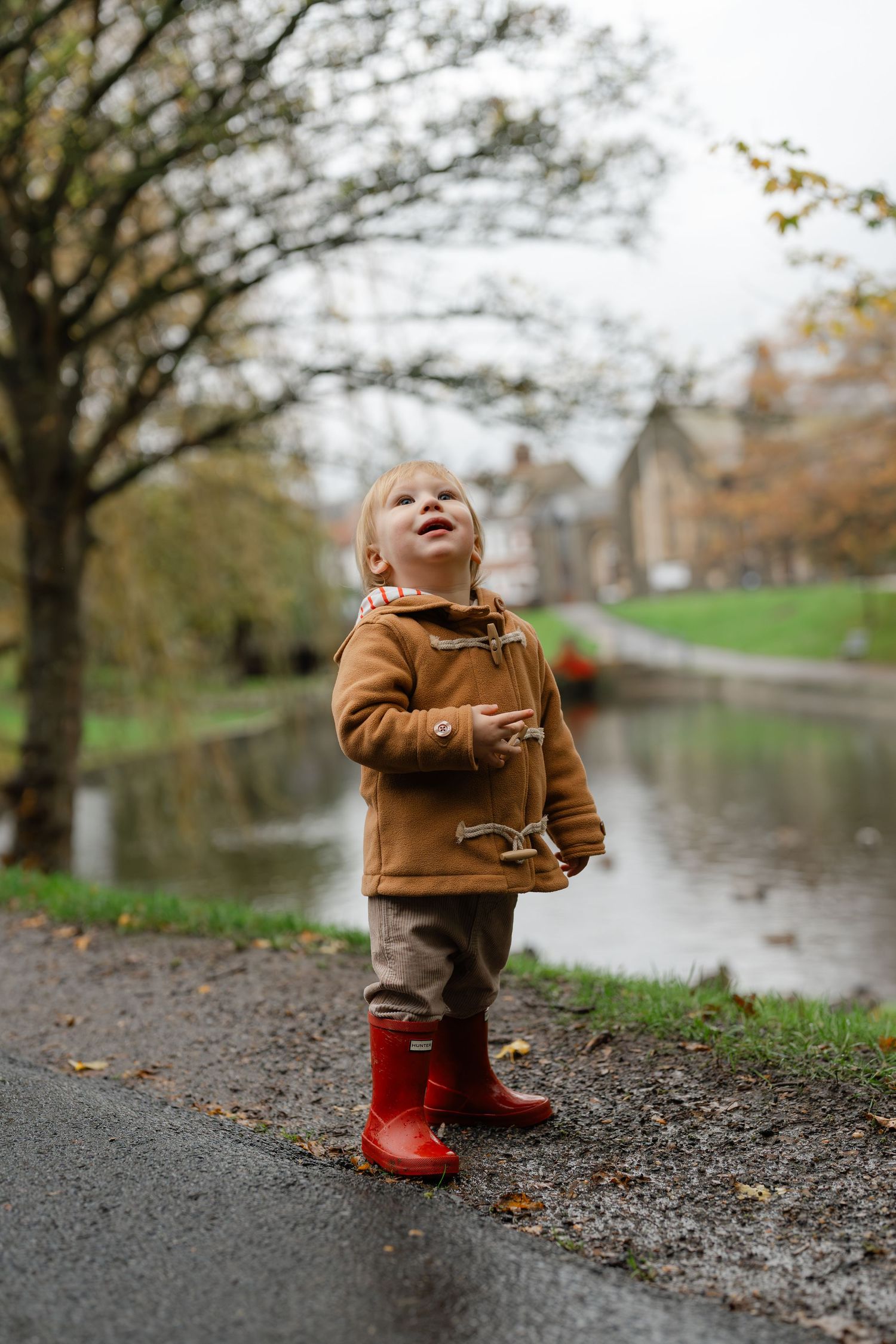 Happy child riding on shoulders through a green countryside path.