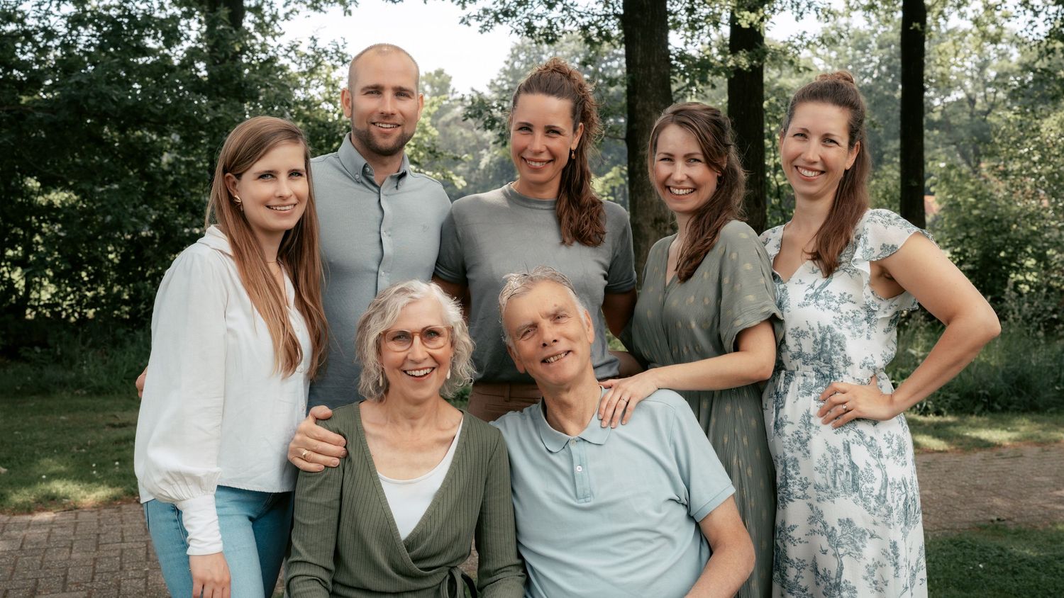 Meer-generatie familieportret in de buitenlucht, ontspannen vastgelegd in een natuurlijke omgeving omringd door bomen.