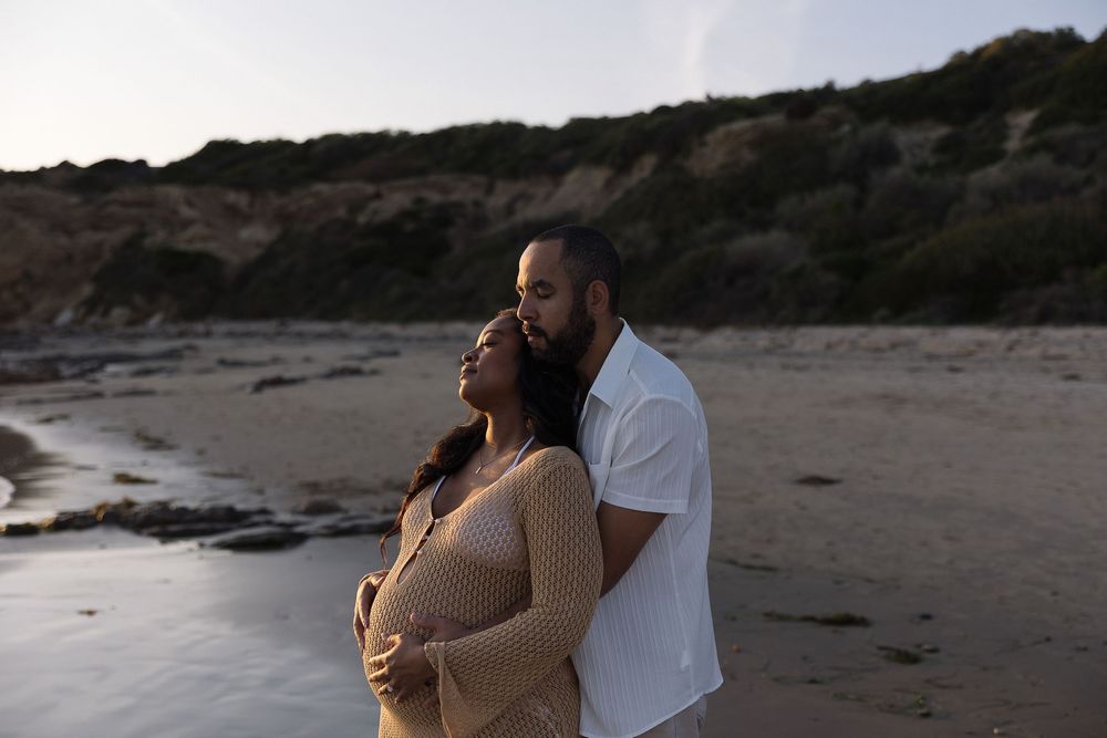 Two people share a romantic moment together on a scenic beach at sunset.