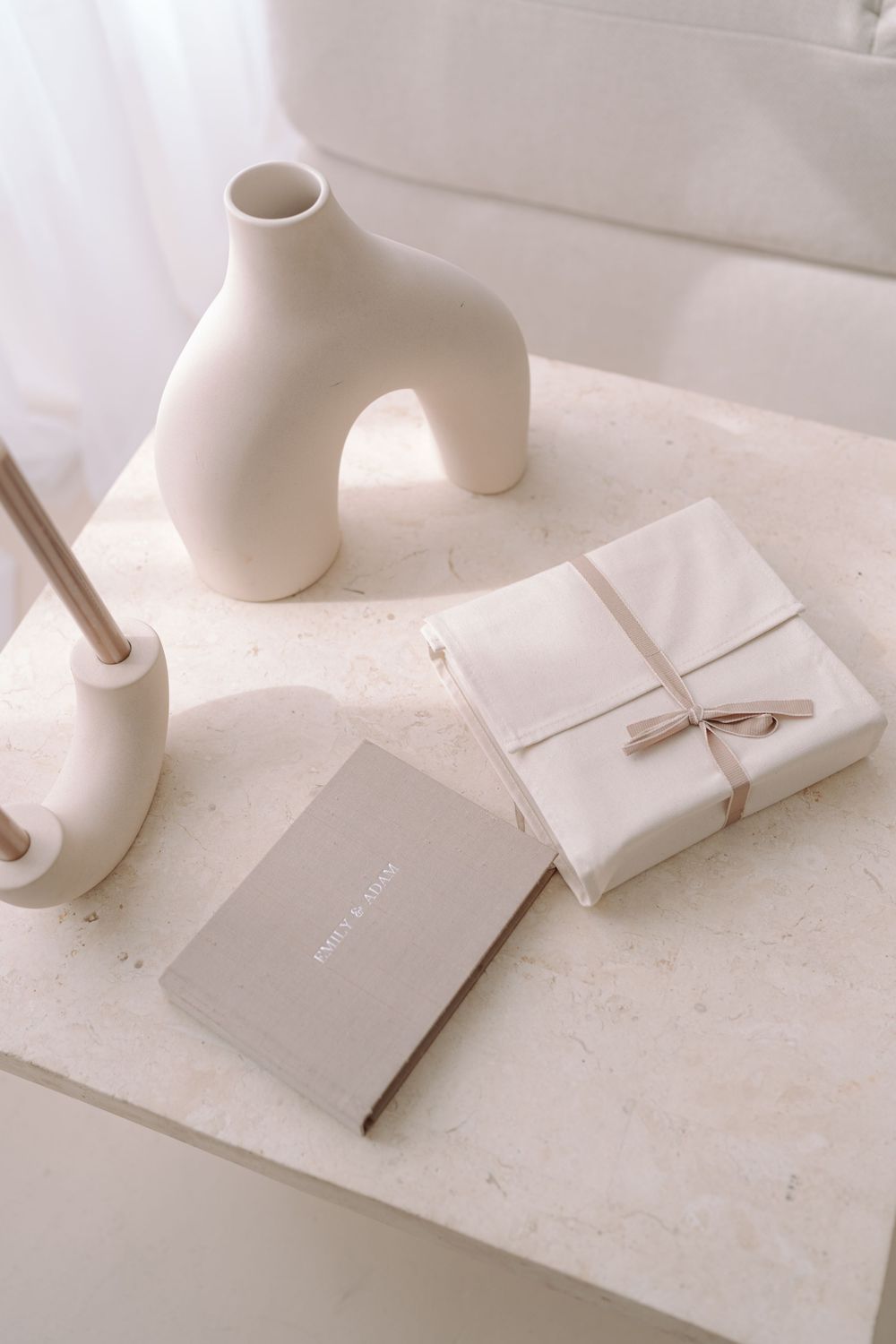 Minimalist white ceramic vases and wrapped packages arranged on marble surface in soft natural lighting.