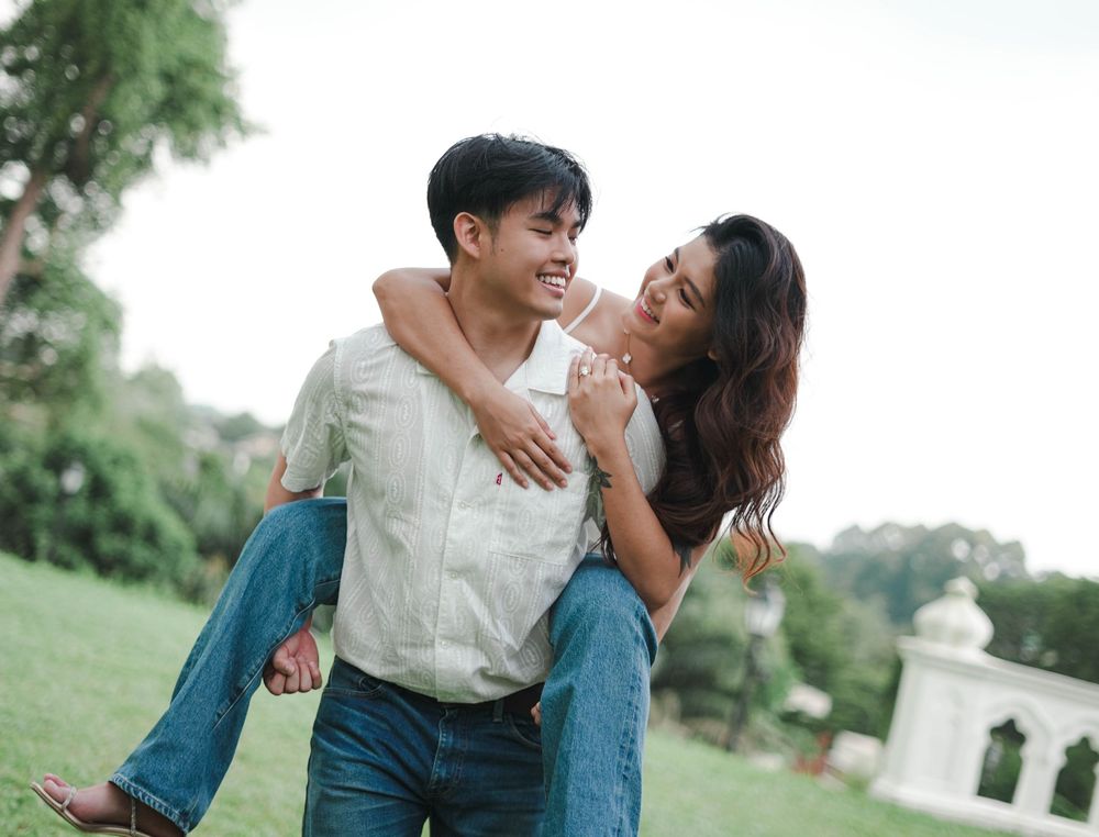 A romantic couple shares tender moments while strolling through a lush park setting.