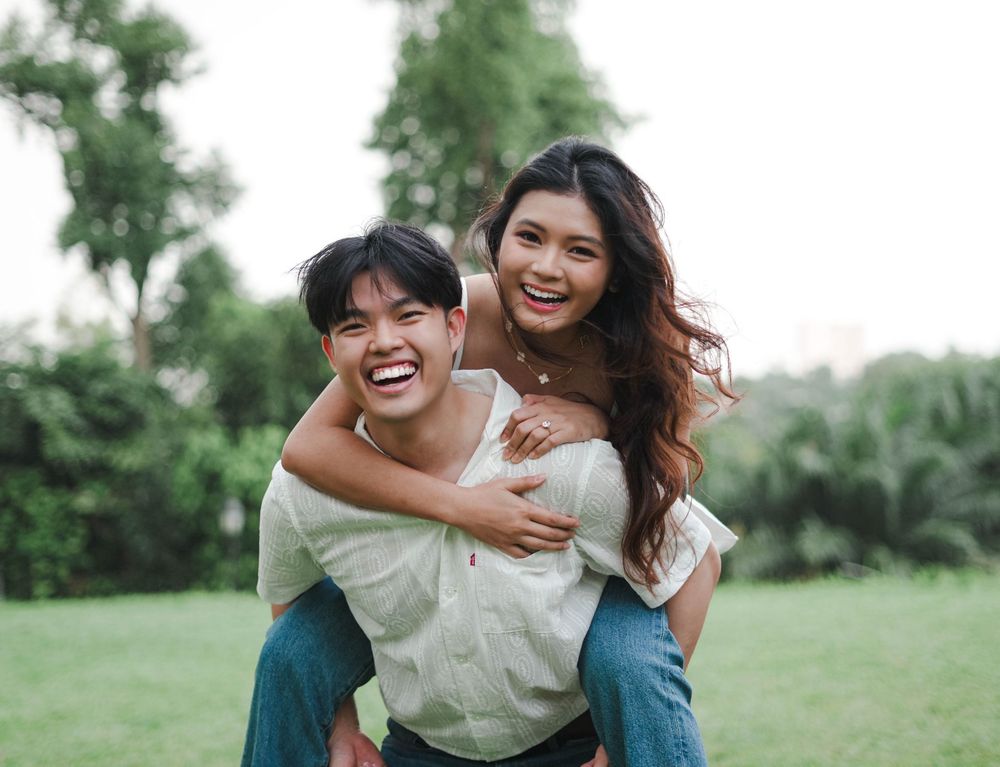 A joyful candid sequence of a couple playfully enjoying themselves in a lush green outdoor setting.