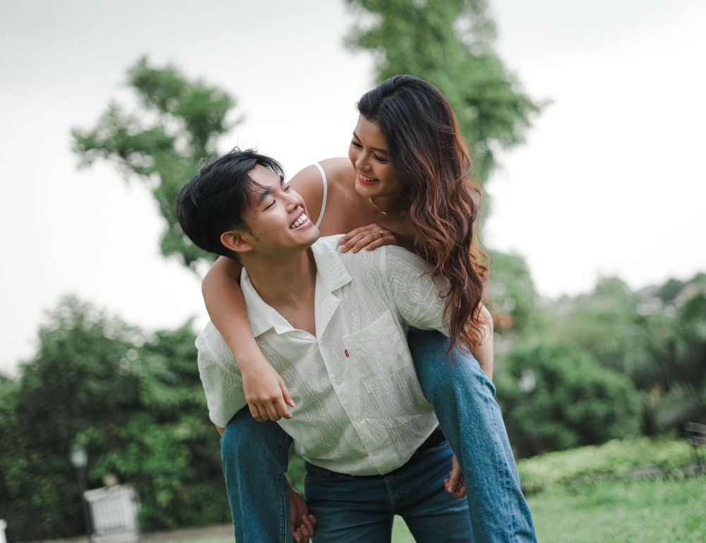 Happy couple sharing a romantic moment together on a grassy hill during a sunny afternoon.
