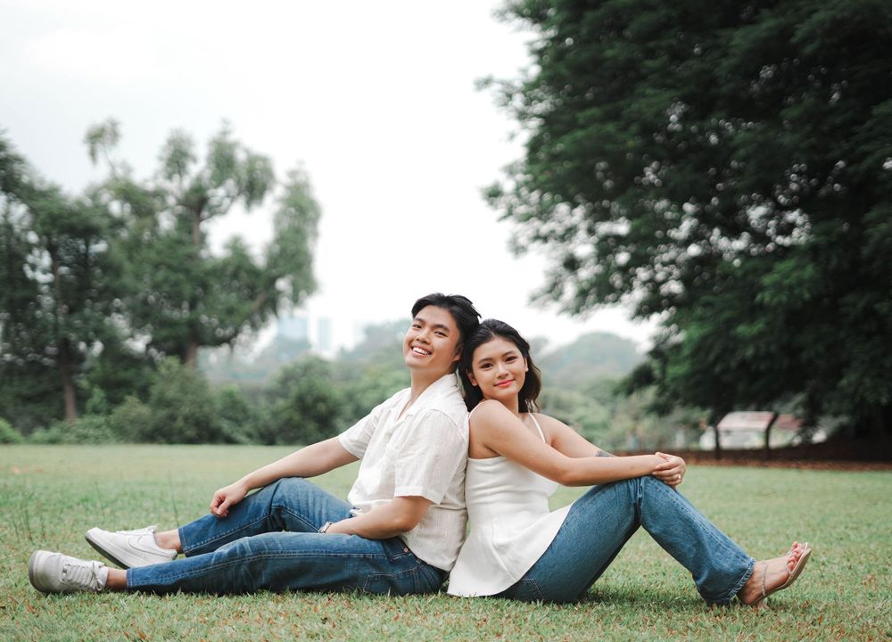 Couple lounging casually on grass enjoying each other's company in an outdoor setting.