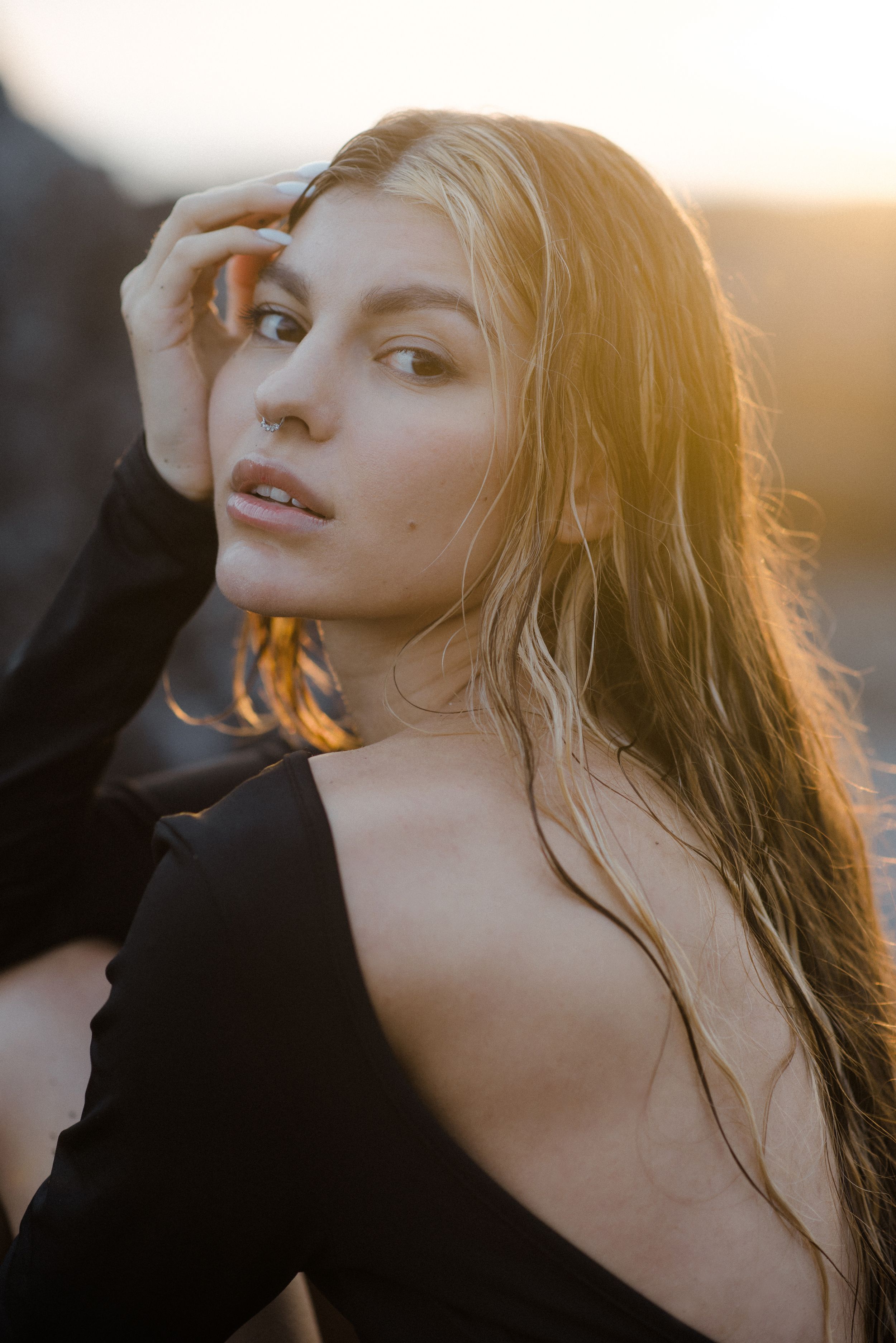 Portrait of a woman in Tenerife in golden sunlight with natural makeup and flowing hair wearing a black top.
