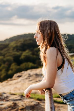 Person relaxing on rocky mountain cliff at sunset with wind blowing through hair.