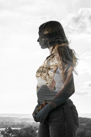 Double exposure portrait overlaid with nature scene showing contemplative pose against cloudy sky.