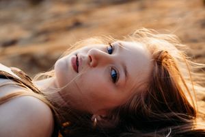 A portrait series of someone illuminated by golden sunset light with auburn hair turning and looking upward during a photoshoot.